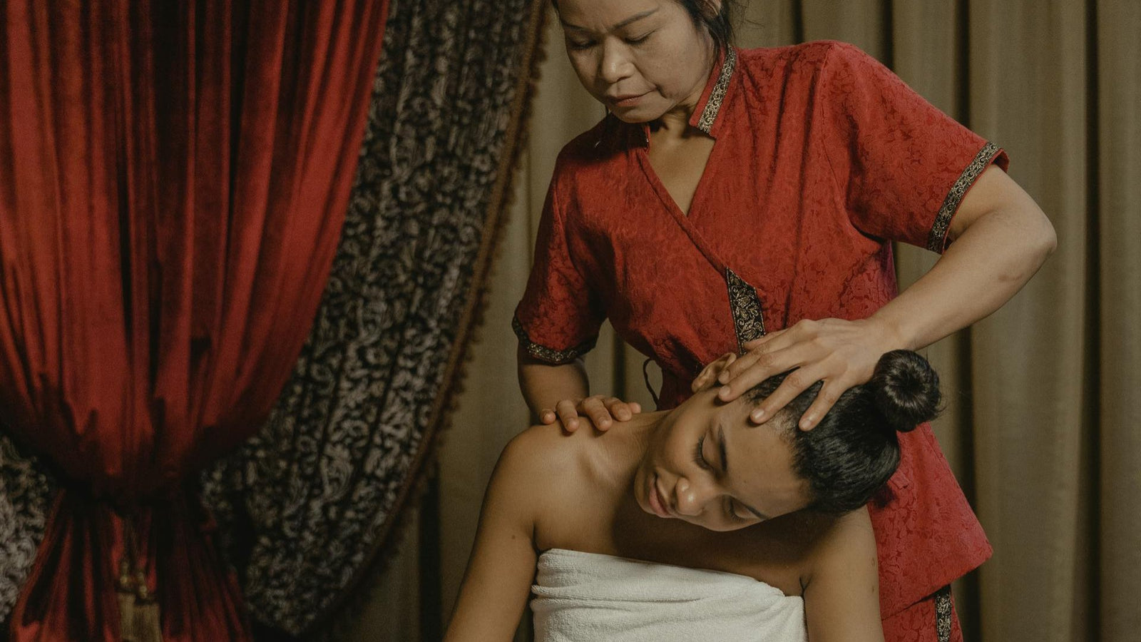 Traditionelle Thai Massage: Eine Masseurin massiert einer Frau den Nacken